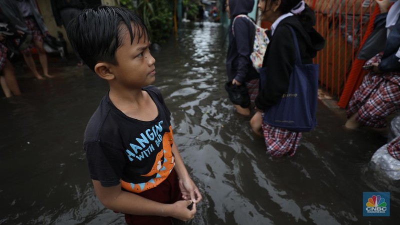 Warga melewati banjir yang merendam di kawasan Puribeta, Ciledug, Tangerang Selatan, Jumat (22/3/2024). (CNBC Indonesia/Tri Susilo)