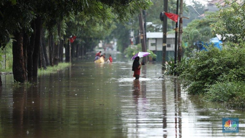 Warga melewati banjir yang merendam di kawasan Puribeta, Ciledug, Tangerang Selatan, Jumat (22/3/2024). (CNBC Indonesia/Tri Susilo)