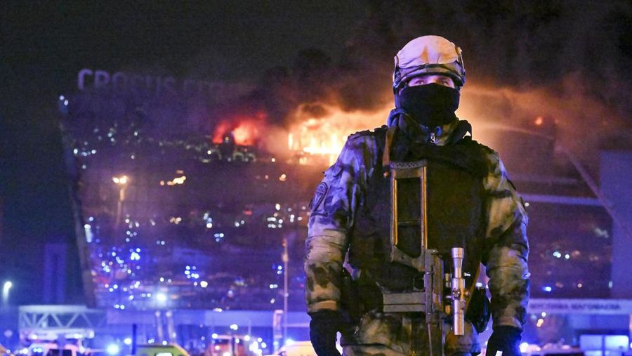Seorang prajurit Rosguardia (Garda Nasional) Rusia mengamankan area ketika kobaran api besar terlihat di Balai Kota Crocus di tepi barat Moskow, Rusia, Jumat, 22 Maret 2024. (AP Photo/Dmitry Serebryakov)