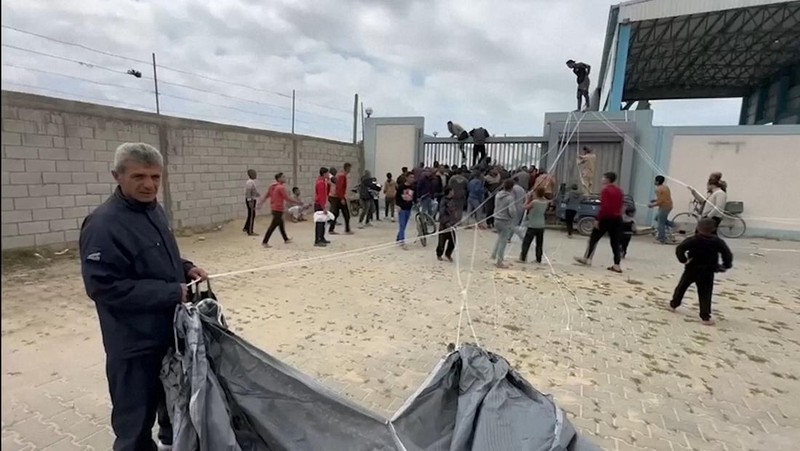 Warga Palestina berbondong-bondong untuk mendapatkan bantuan yang dijatuhkan dari udara pada Jumat (22/3) di Muraj, Gaza selatan. (Tangkapan Layar video AP)