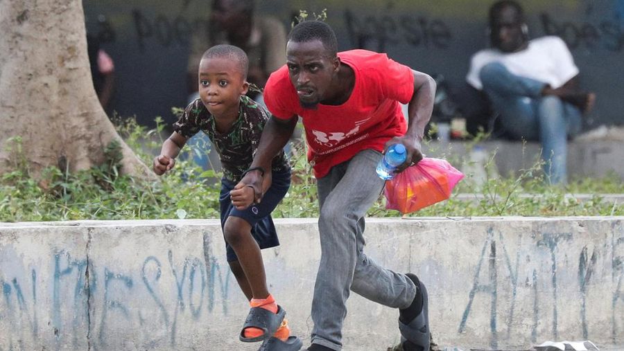 Seorang wanita berlindung dari tembakan di dekat Istana Nasional, di Port-au-Prince, Haiti 21 Maret 2024. (REUTERS/Ralph Tedy Erol)