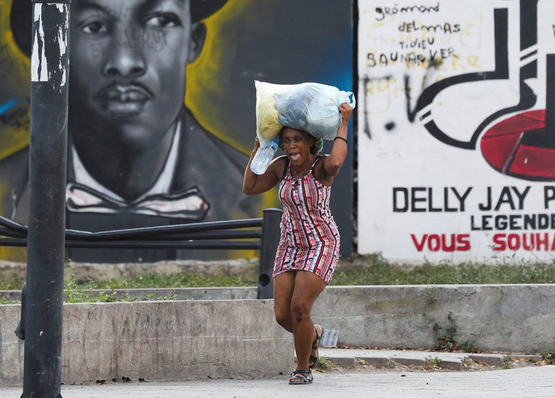 Seorang wanita berlindung dari tembakan di dekat Istana Nasional, di Port-au-Prince, Haiti 21 Maret 2024. (REUTERS/Ralph Tedy Erol)