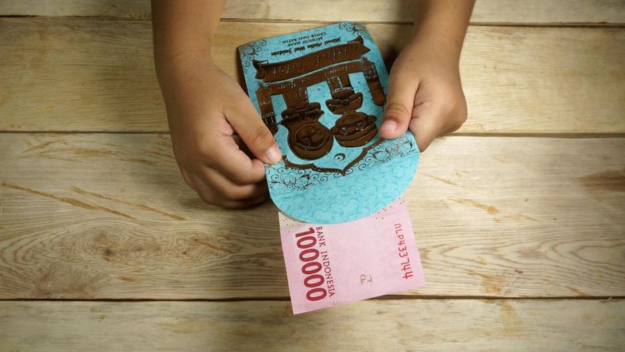 Hand of young kid holding indonesian money. Rupiah/IDR money.