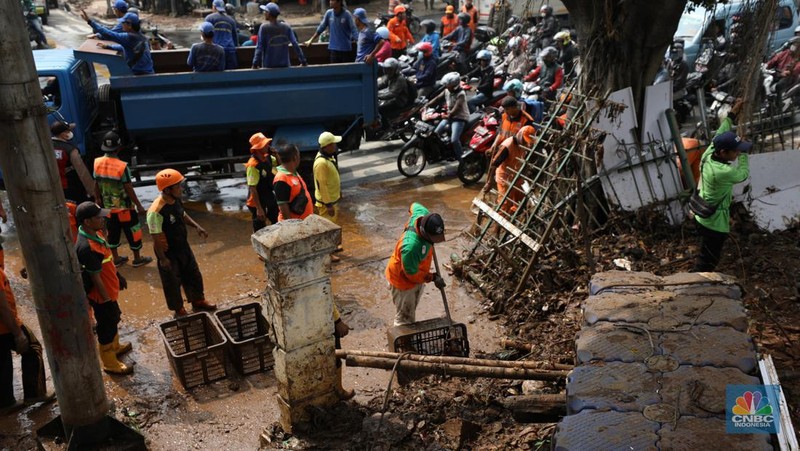 Petugas Penanganan Prasarana dan Sarana Umum (PPSU) membersihkan sisa-sisa sampah di proyek tanggul kali Hek kawasan Kramat Jati jati, Jakarta, Senin (25/3/2024). (CNBC Indonesia/Tri Susilo)