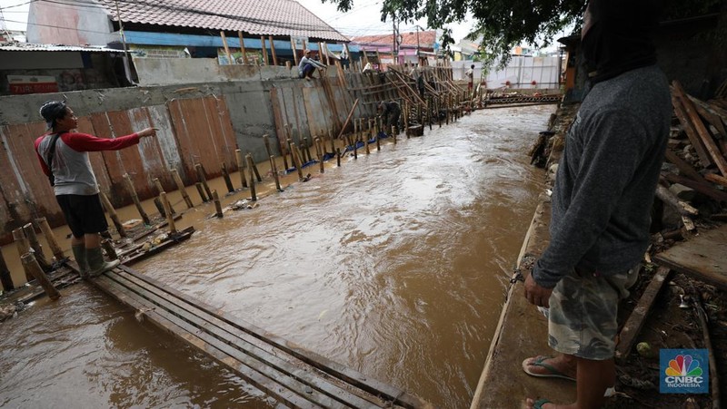 Petugas Penanganan Prasarana dan Sarana Umum (PPSU) membersihkan sisa-sisa sampah di proyek tanggul kali Hek kawasan Kramat Jati jati, Jakarta, Senin (25/3/2024). (CNBC Indonesia/Tri Susilo)