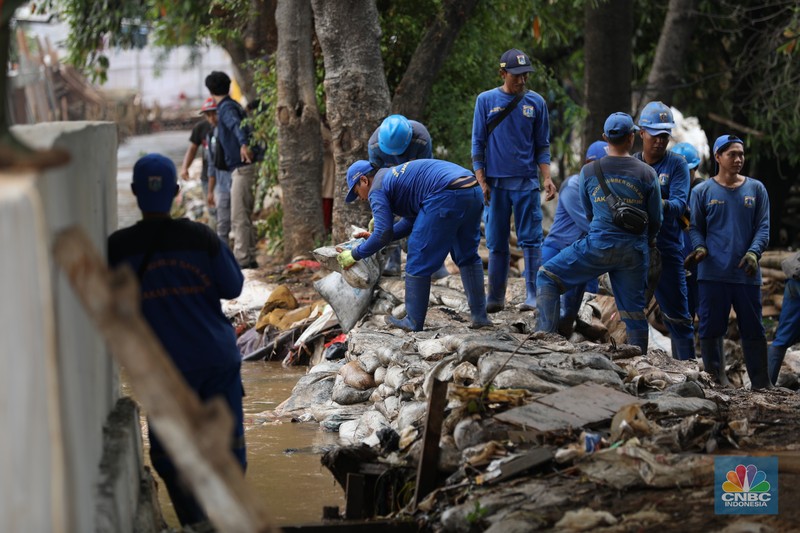 Petugas Penanganan Prasarana dan Sarana Umum (PPSU) membersihkan sisa-sisa sampah di proyek tanggul kali Hek kawasan Kramat Jati jati, Jakarta, Senin (25/3/2024). Petugas Penanganan Prasarana dan Sarana Umum (PPSU) membersihkan sisa-sisa sampah di proyek tanggul kali Hek kawasan Kramat Jati jati, Jakarta, Senin (25/3/2024). (CNBC Indonesia/Tri Susilo)