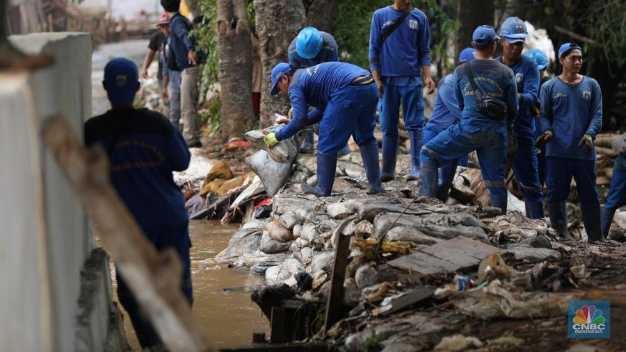 Petugas Penanganan Prasarana dan Sarana Umum (PPSU) membersihkan sisa-sisa sampah di proyek tanggul kali Hek kawasan Kramat Jati jati, Jakarta, Senin (25/3/2024). (CNBC Indonesia/Tri Susilo)