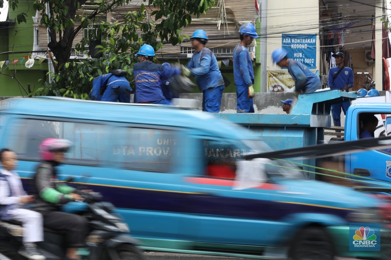Petugas Penanganan Prasarana dan Sarana Umum (PPSU) membersihkan sisa-sisa sampah di proyek tanggul kali Hek kawasan Kramat Jati jati, Jakarta, Senin (25/3/2024). (CNBC Indonesia/Tri Susilo)