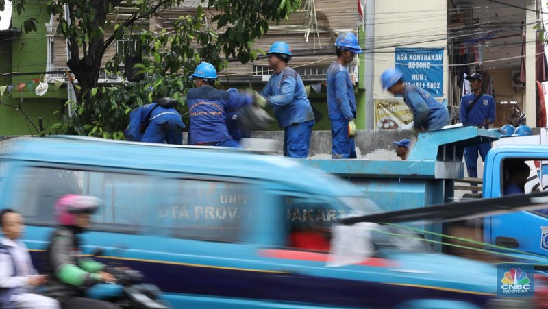 Petugas Penanganan Prasarana dan Sarana Umum (PPSU) membersihkan sisa-sisa sampah di proyek tanggul kali Hek kawasan Kramat Jati jati, Jakarta, Senin (25/3/2024). (CNBC Indonesia/Tri Susilo)