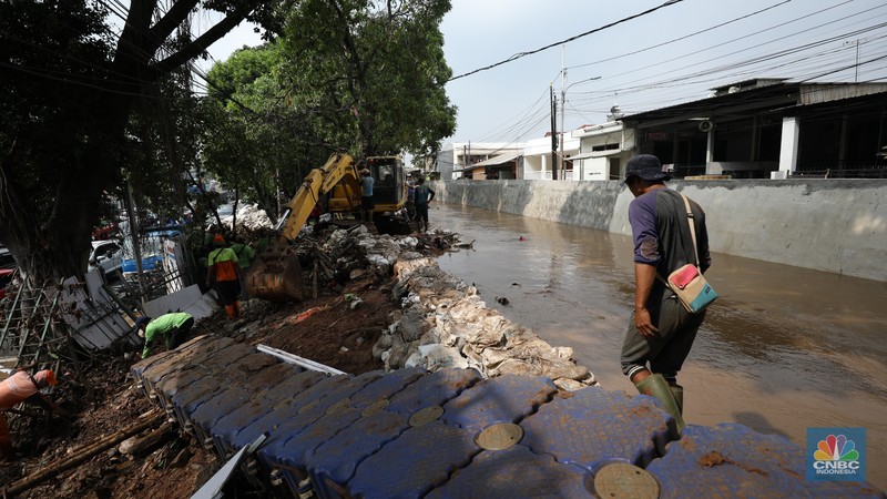 Petugas Penanganan Prasarana dan Sarana Umum (PPSU) membersihkan sisa-sisa sampah di proyek tanggul kali Hek kawasan Kramat Jati jati, Jakarta, Senin (25/3/2024). (CNBC Indonesia/Tri Susilo)