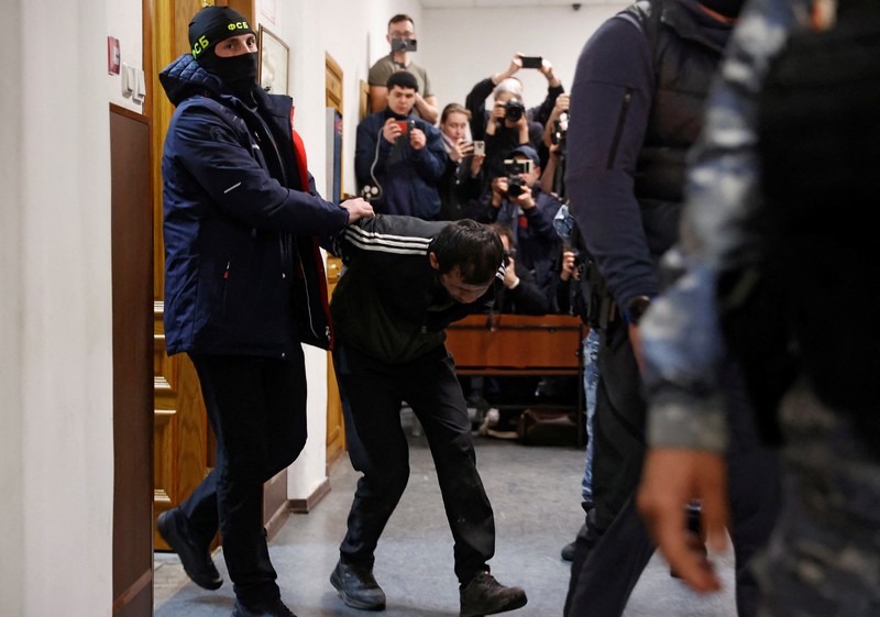 Shamsidin Fariduni, tersangka penembakan di tempat konser Balai Kota Crocus, dikawal sebelum sidang di pengadilan distrik Basmanny di Moskow, Rusia 25 Maret 2024. (REUTERS/Yulia Morozova)