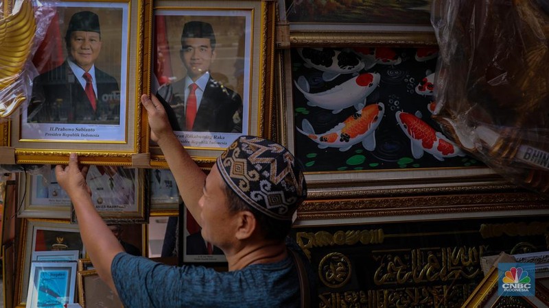 Penjual menata poster dengan foto pasangan Capres-Cawapres nomor urut 02, Prabowo Subianto dan Gibran Rakabuming Raka yang dijual pada kiosnya di kawasan Pasar Baru, Jakarta, Selasa (26/3/2024). (CNBC Indonesia/Faisal Rahman)