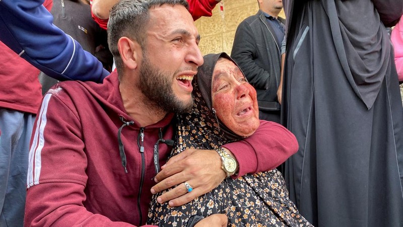 The mother of Palestinian Khalil Abu Shamala, who was killed in an Israeli strike, mourns with her face stained with his blood as Khalil's brother reacts, amid the ongoing conflict between Israel and Hamas, at Al-Aqsa hospital in Deir Al-Balah in the central Gaza Strip, March 27, 2024. REUTERS/Doaa Rouqa     TPX IMAGES OF THE DAY
