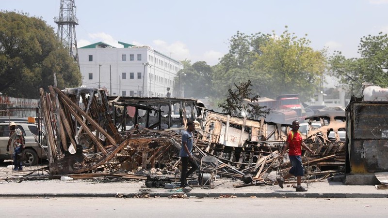 Seorang pria bereaksi di samping sisa-sisa kendaraan yang hangus di dekat istana presiden, setelah dibakar oleh geng, ketika kekerasan menyebar dan geng bersenjata memperluas kendali mereka atas ibu kota, di Port-au-Prince, Haiti, 25 Maret 2024. (REUTERS/Ralph Tedy Erol)