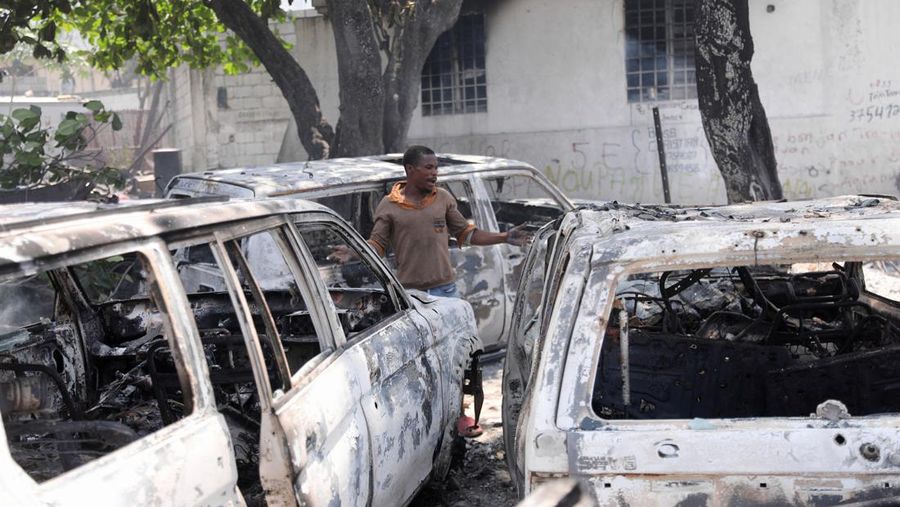 Seorang pria bereaksi di samping sisa-sisa kendaraan yang hangus di dekat istana presiden, setelah dibakar oleh geng, ketika kekerasan menyebar dan geng bersenjata memperluas kendali mereka atas ibu kota, di Port-au-Prince, Haiti, 25 Maret 2024. (REUTERS/Ralph Tedy Erol)