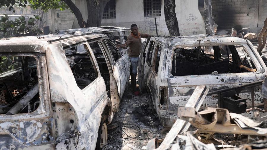 Seorang pria bereaksi di samping sisa-sisa kendaraan yang hangus di dekat istana presiden, setelah dibakar oleh geng, ketika kekerasan menyebar dan geng bersenjata memperluas kendali mereka atas ibu kota, di Port-au-Prince, Haiti, 25 Maret 2024. (REUTERS/Ralph Tedy Erol)
