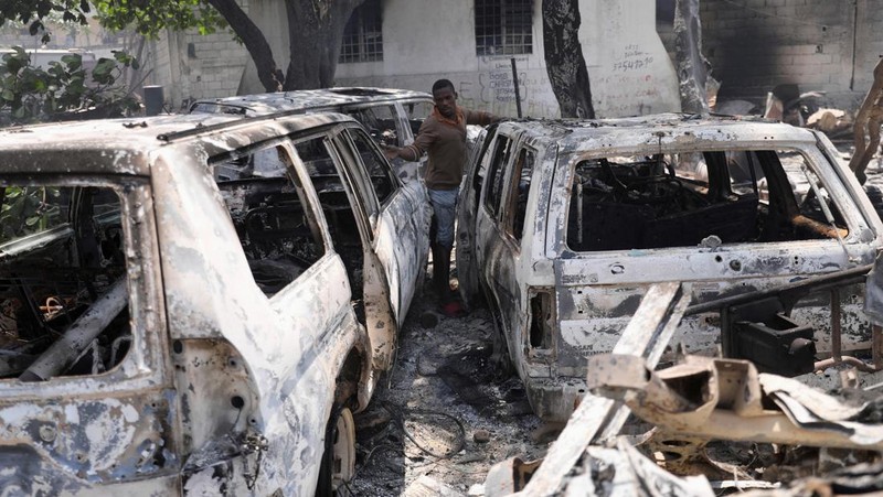 Seorang pria bereaksi di samping sisa-sisa kendaraan yang hangus di dekat istana presiden, setelah dibakar oleh geng, ketika kekerasan menyebar dan geng bersenjata memperluas kendali mereka atas ibu kota, di Port-au-Prince, Haiti, 25 Maret 2024. (REUTERS/Ralph Tedy Erol)