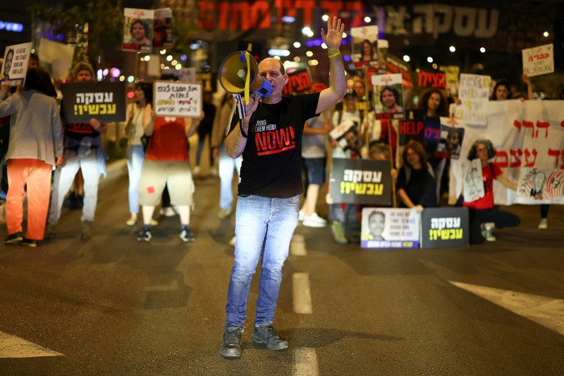Demonstran menunjukkan tanda-tanda di tengah lalu lintas pada protes menuntut pembebasan sandera yang diculik dalam serangan mematikan 7 Oktober di Israel oleh kelompok Islam Palestina Hamas dari Gaza, di Tel Aviv, Israel 27 Maret 2024. (REUTERS/Hannah McKay)