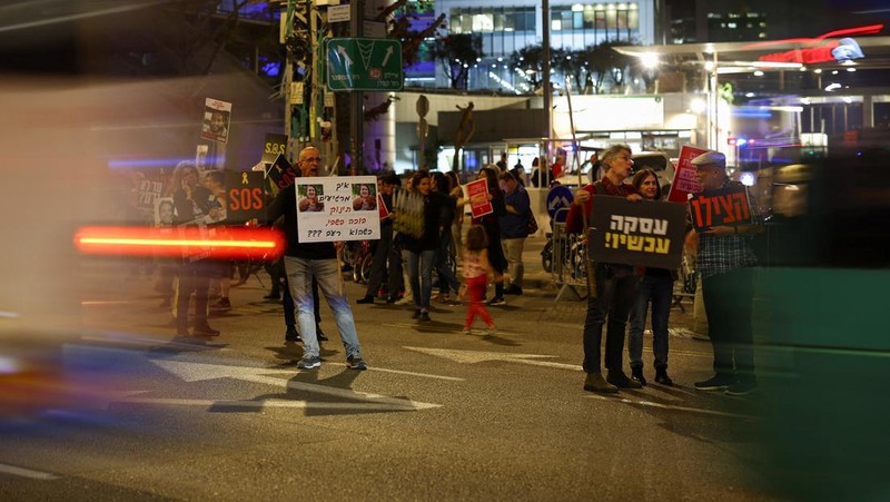 Demonstran menunjukkan tanda-tanda di tengah lalu lintas pada protes menuntut pembebasan sandera yang diculik dalam serangan mematikan 7 Oktober di Israel oleh kelompok Islam Palestina Hamas dari Gaza, di Tel Aviv, Israel 27 Maret 2024. (REUTERS/Hannah McKay)