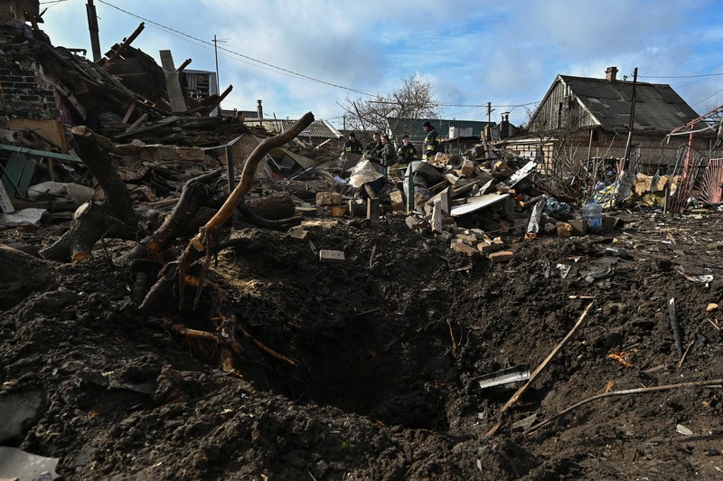 Rescuers work at the site of damaged residential buildings, next to a crater that appeared during a Russian drone strike, amid Russia's attack on Ukraine, in Zaporizhzhia, Ukraine March 28, 2024. REUTERS/Stringer