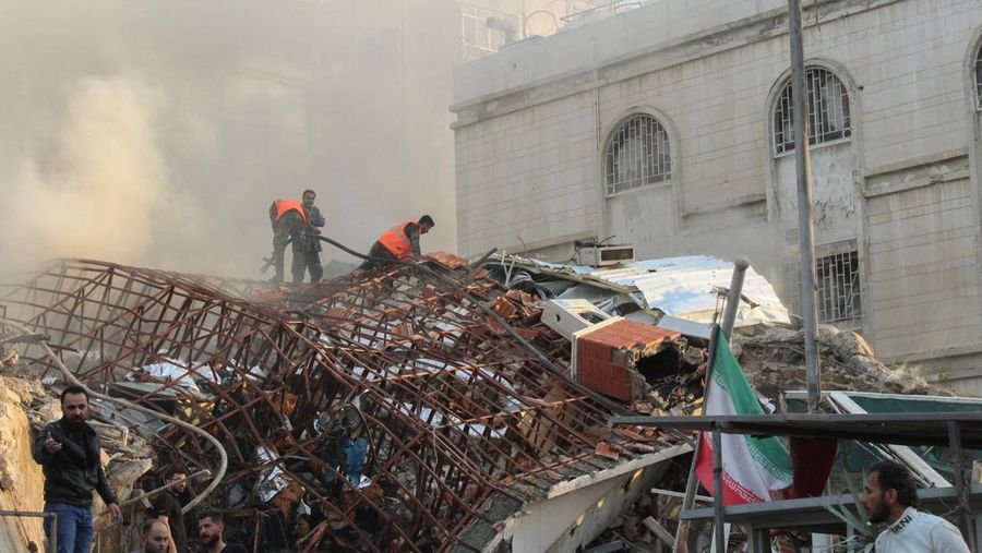 Anggota pertahanan sipil berdiri di dekat lokasi yang rusak setelah apa yang digambarkan media Suriah dan Iran sebagai serangan udara Israel terhadap konsulat Iran di ibu kota Suriah, Damaskus, 1 April 2024. (REUTERS/Firas Makdesi)