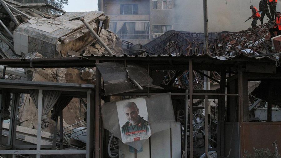 Foto mendiang komandan militer senior Iran Jenderal Qassem Soleimani tergantung di tengah reruntuhan setelah apa yang digambarkan media Suriah dan Iran sebagai serangan udara Israel terhadap konsulat Iran di ibu kota Suriah, Damaskus, 1 April 2024. (REUTERS/Firas Makdesi)