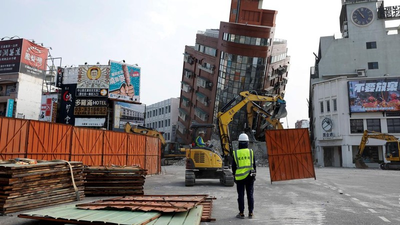 Orang-orang mengendarai sepeda motor di dekat lokasi bangunan runtuh pasca gempa, di Hualien, Taiwan 4 April 2024. (REUTERS/Carlos Garcia Rawlins)