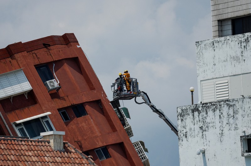Seorang wanita membawa barang dagangan dari toko sepeda di gedung yang rusak saat orang memindahkan barang dagangan dan barang berharga ke luar gedung, pasca gempa, di Hualien, Taiwan, 4 April 2024. (REUTERS/Carlos Garcia Rawlins)