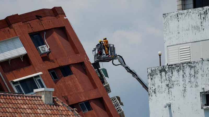 Seorang wanita membawa barang dagangan dari toko sepeda di gedung yang rusak saat orang memindahkan barang dagangan dan barang berharga ke luar gedung, pasca gempa, di Hualien, Taiwan, 4 April 2024. (REUTERS/Carlos Garcia Rawlins)