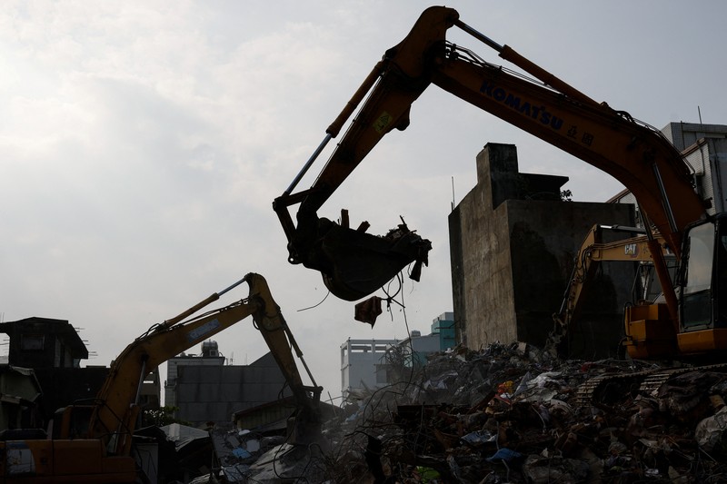 Orang-orang mengendarai sepeda motor di dekat lokasi bangunan runtuh pasca gempa, di Hualien, Taiwan 4 April 2024. (REUTERS/Carlos Garcia Rawlins)
