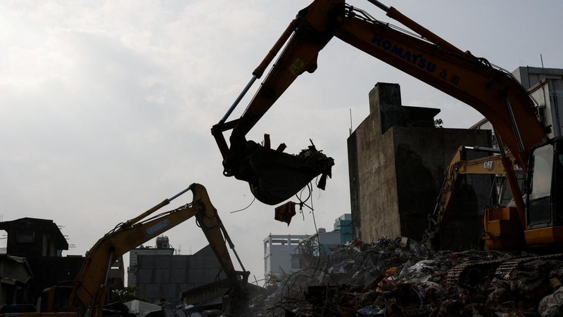 Orang-orang mengendarai sepeda motor di dekat lokasi bangunan runtuh pasca gempa, di Hualien, Taiwan 4 April 2024. (REUTERS/Carlos Garcia Rawlins)