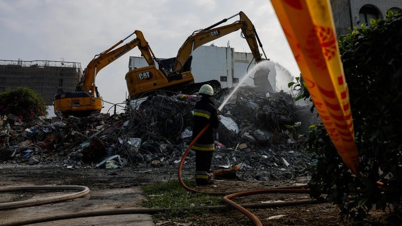 Orang-orang mengendarai sepeda motor di dekat lokasi bangunan runtuh pasca gempa, di Hualien, Taiwan 4 April 2024. (REUTERS/Carlos Garcia Rawlins)