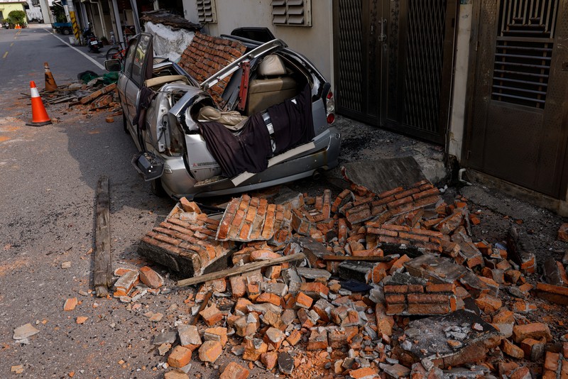 Seorang wanita membawa barang dagangan dari toko sepeda di gedung yang rusak saat orang memindahkan barang dagangan dan barang berharga ke luar gedung, pasca gempa, di Hualien, Taiwan, 4 April 2024. (REUTERS/Carlos Garcia Rawlins)