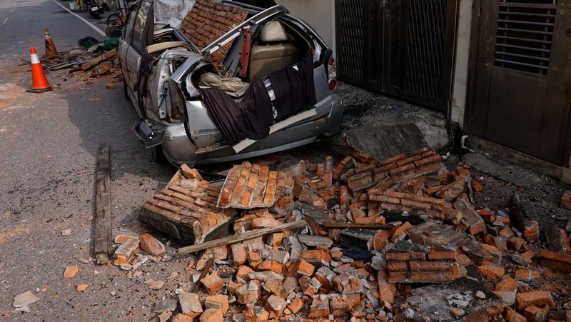 Seorang wanita membawa barang dagangan dari toko sepeda di gedung yang rusak saat orang memindahkan barang dagangan dan barang berharga ke luar gedung, pasca gempa, di Hualien, Taiwan, 4 April 2024. (REUTERS/Carlos Garcia Rawlins)