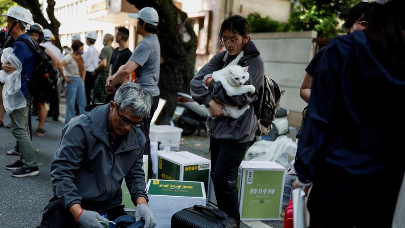 Seorang wanita membawa barang dagangan dari toko sepeda di gedung yang rusak saat orang memindahkan barang dagangan dan barang berharga ke luar gedung, pasca gempa, di Hualien, Taiwan, 4 April 2024. (REUTERS/Carlos Garcia Rawlins)
