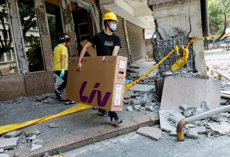 Seorang wanita membawa barang dagangan dari toko sepeda di gedung yang rusak saat orang memindahkan barang dagangan dan barang berharga ke luar gedung, pasca gempa, di Hualien, Taiwan, 4 April 2024. (REUTERS/Carlos Garcia Rawlins)