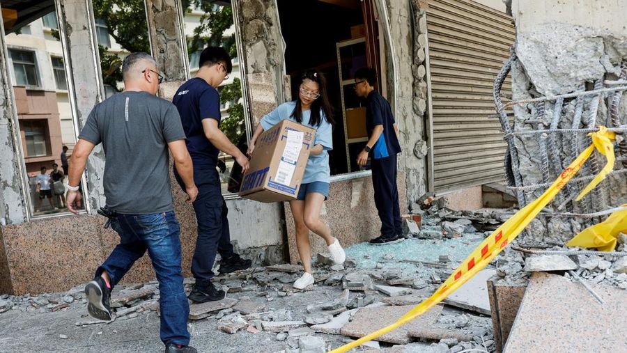 Seorang wanita membawa barang dagangan dari toko sepeda di gedung yang rusak saat orang memindahkan barang dagangan dan barang berharga ke luar gedung, pasca gempa, di Hualien, Taiwan, 4 April 2024. (REUTERS/Carlos Garcia Rawlins)