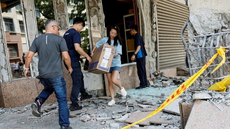 Seorang wanita membawa barang dagangan dari toko sepeda di gedung yang rusak saat orang memindahkan barang dagangan dan barang berharga ke luar gedung, pasca gempa, di Hualien, Taiwan, 4 April 2024. (REUTERS/Carlos Garcia Rawlins)