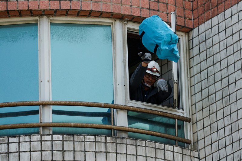 Seorang wanita membawa barang dagangan dari toko sepeda di gedung yang rusak saat orang memindahkan barang dagangan dan barang berharga ke luar gedung, pasca gempa, di Hualien, Taiwan, 4 April 2024. (REUTERS/Carlos Garcia Rawlins)