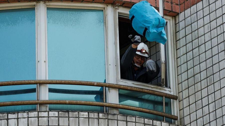 Seorang wanita membawa barang dagangan dari toko sepeda di gedung yang rusak saat orang memindahkan barang dagangan dan barang berharga ke luar gedung, pasca gempa, di Hualien, Taiwan, 4 April 2024. (REUTERS/Carlos Garcia Rawlins)