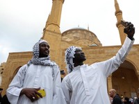 Jemaah Muslim dari Sudan berfoto selfie sambil mengenakan keffiyeh saat salat Idul Fitri, menandai akhir bulan suci Ramadhan, di luar masjid Al-Amin di pusat kota Beirut, Lebanon 10 April 2024. (REUTERS/Mohamed Azakir)