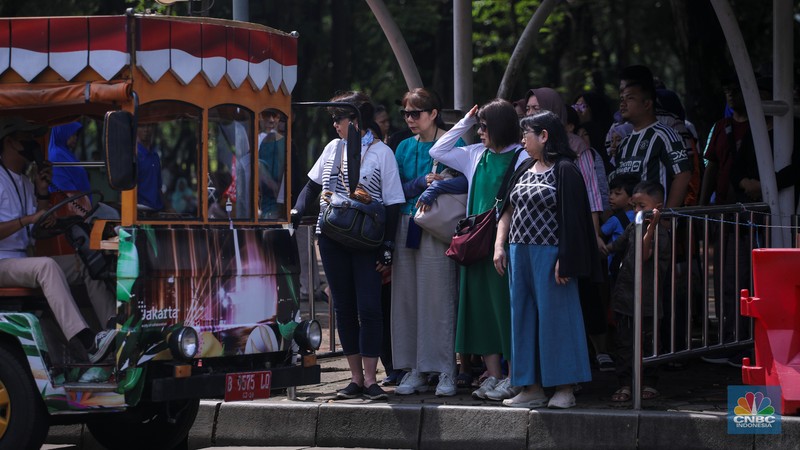 Sejumlah pengunjung berwisata di Kawasan Monumen Nasional (Monas), Jakarta, Jumat (12/4/2024). (CNBC Indonesia/Faisal Rahman)