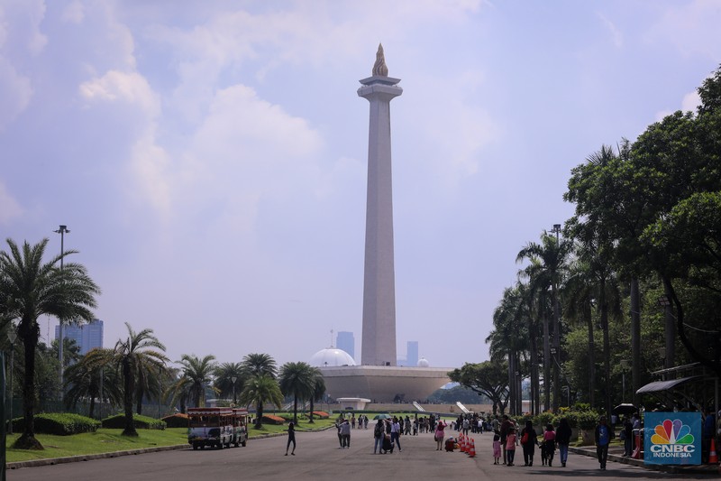 Sejumlah pengunjung berwisata di Kawasan Monumen Nasional (Monas), Jakarta, Jumat (12/4/2024). (CNBC Indonesia/Faisal Rahman)