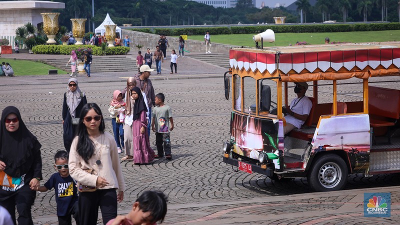 Sejumlah pengunjung berwisata di Kawasan Monumen Nasional (Monas), Jakarta, Jumat (12/4/2024). (CNBC Indonesia/Faisal Rahman)