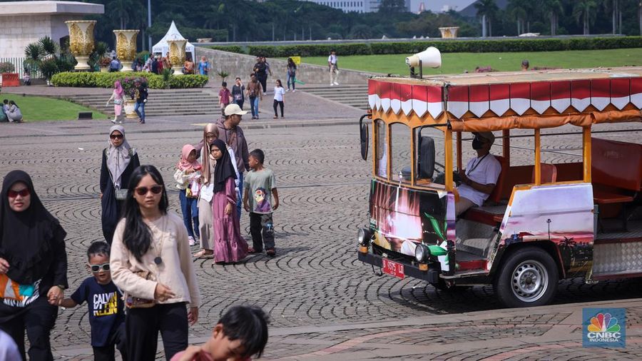 Sejumlah pengunjung berwisata di Kawasan Monumen Nasional (Monas), Jakarta, Jumat (12/4/2024). (CNBC Indonesia/Faisal Rahman)