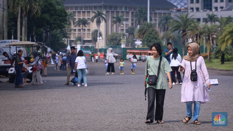 Sejumlah pengunjung berwisata di Kawasan Monumen Nasional (Monas), Jakarta, Jumat (12/4/2024). (CNBC Indonesia/Faisal Rahman)