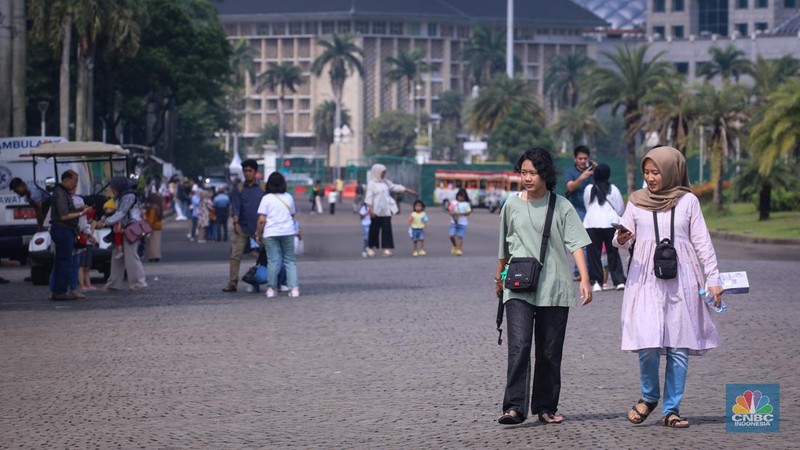 Sejumlah pengunjung berwisata di Kawasan Monumen Nasional (Monas), Jakarta, Jumat (12/4/2024). (CNBC Indonesia/Faisal Rahman)