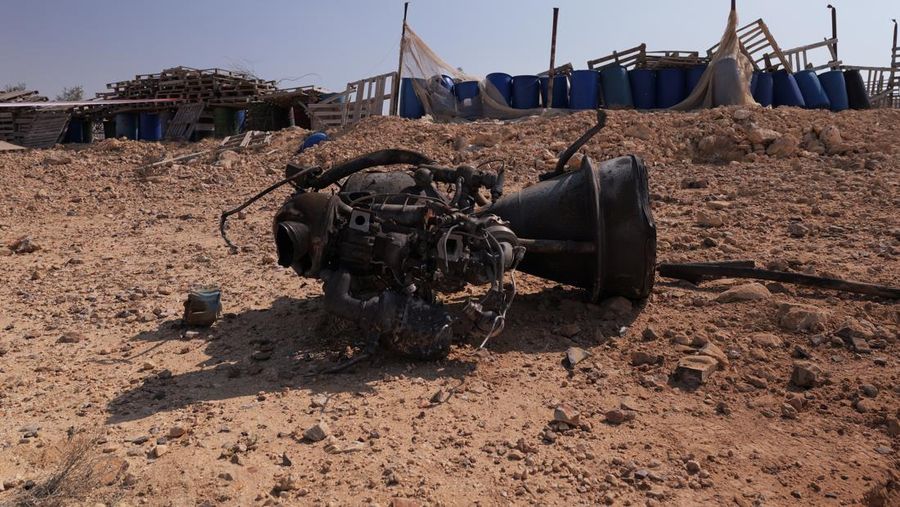 Seorang petugas polisi dan warga memeriksa sisa-sisa pendorong roket yang, menurut pihak berwenang Israel, melukai parah seorang gadis berusia 7 tahun, setelah Iran meluncurkan drone dan rudal ke arah Israel, dekat Arad, Israel, 14 April 2024. (REUTERS/Christophe van der Perre)