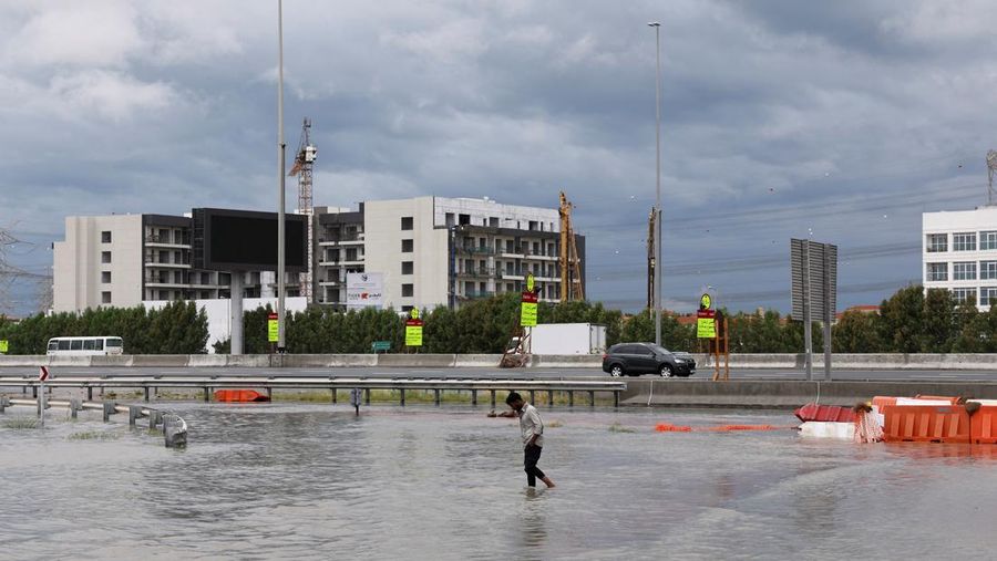 Seseorang berjalan melewati air di jalan yang banjir setelah hujan lebat di Dubai, Uni Emirat Arab, 16 April 2024. (REUTERS/Amr Alfiky)