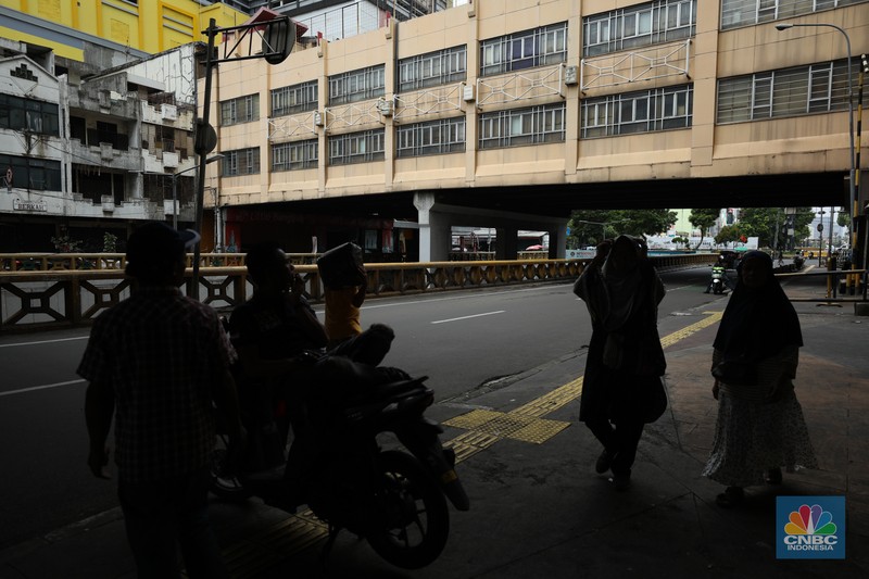Warga melintas di depan Pasar Tanah Abang Blok A yang tutup di Jakarta, Selasa (16/4/2024). (CNBC Indonesia/Tri Susilo)